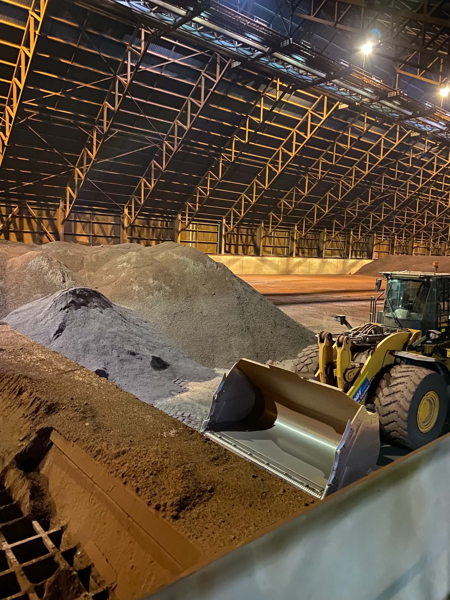 Loader operating beside a bulk commodity stockpile